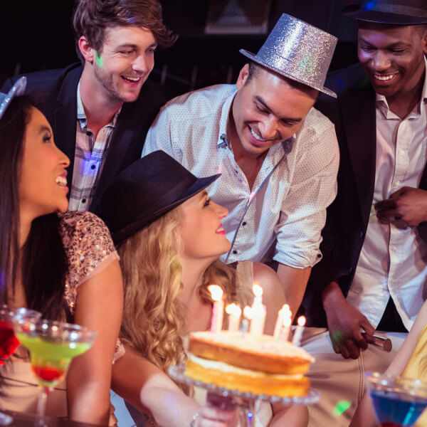 Un groupe de personnes célébrant un anniversaire dans une salle festive à Montréal, entouré de décorations colorées.